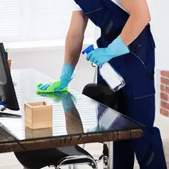 Cleaner cleaning a desk at an office in West Midlands