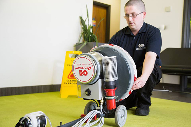 Man in Flawless Cleaning Ltd uniform fixing his carpet washing machine