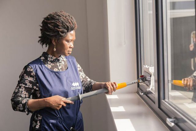 Woman with Flawless Cleaning Ltd uniform washing windows